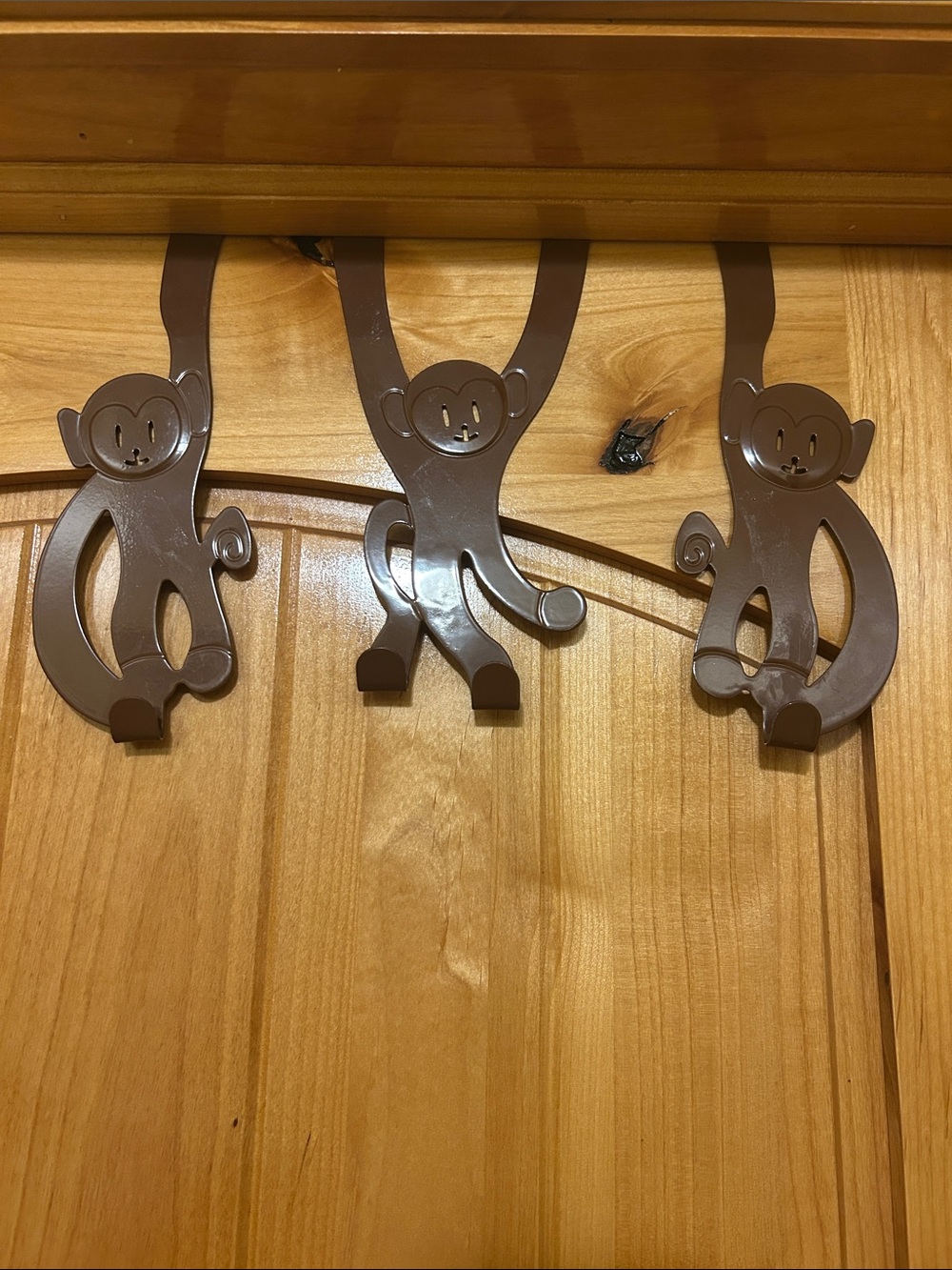 A set of 3 whimsical brown metal monkey over-the-door hooks